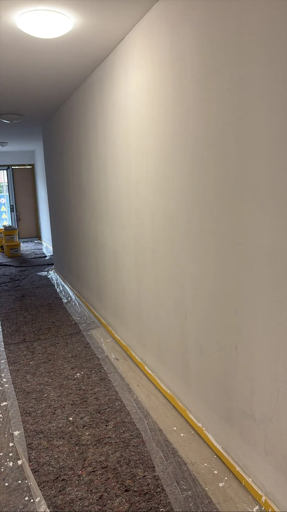 Frisch beschichtete Flurwand mit abgedecktem Boden während der Ausführung