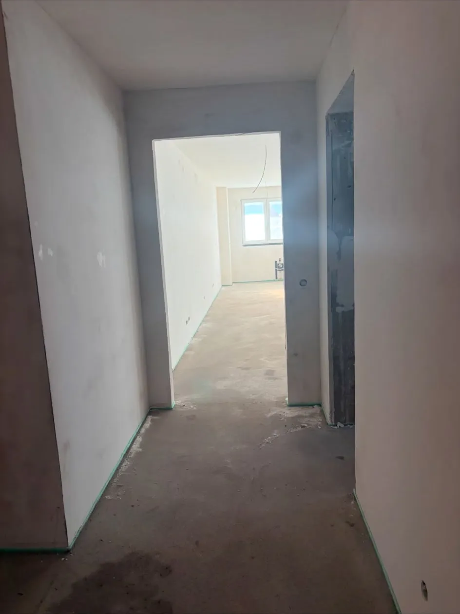 Gespachtelter Wohnungsflur im Rohbau mit Blick in den Wohnraum