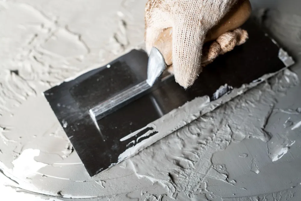Spachtelmasse wird mit der Kelle auf eine Wand aufgezogen