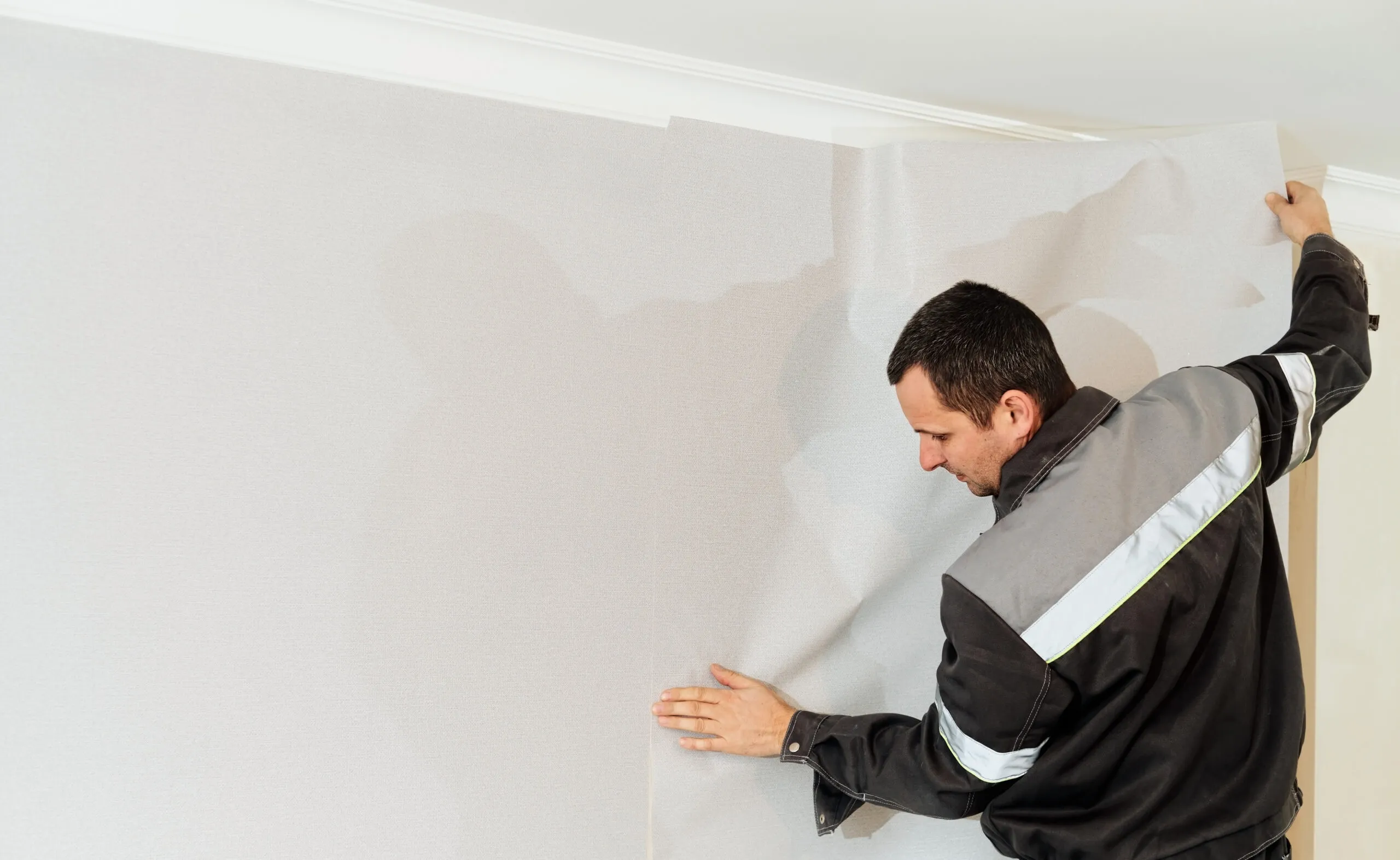 Handwerker bringt eine Tapete an einer Wand in Dortmund an