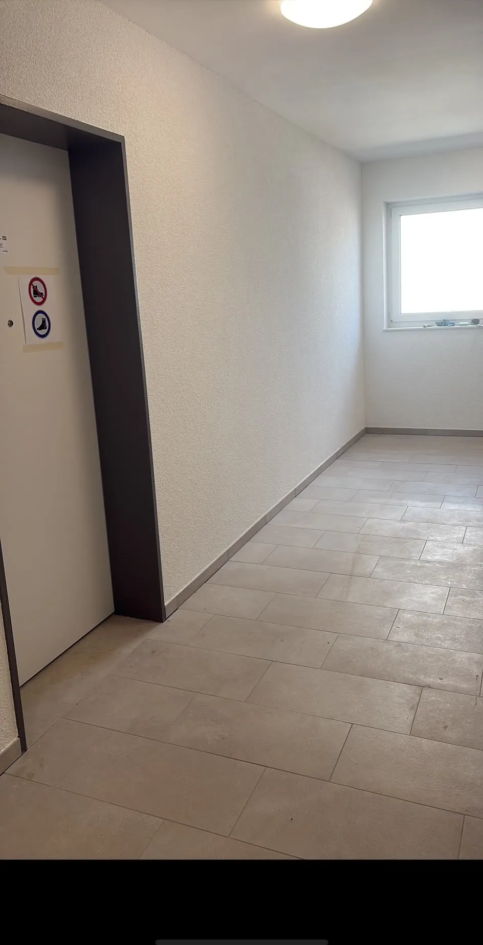 Fertiger Treppenhausflur mit Reibeputzwand und gefliestem Boden