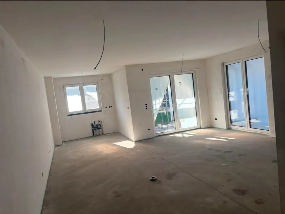 Großer Wohnraum mit gespachtelten Wänden und Fensterfront vor den Anstricharbeiten