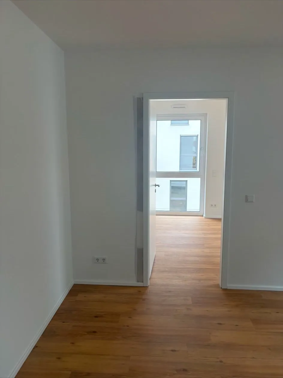 Fertig gestrichene Wohnung mit Parkettboden und Blick in den Nebenraum