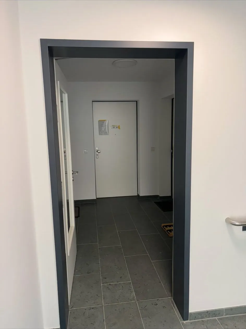 Fertiger Wohnungseingang mit dunkel lackierter Zarge und gefliestem Flur